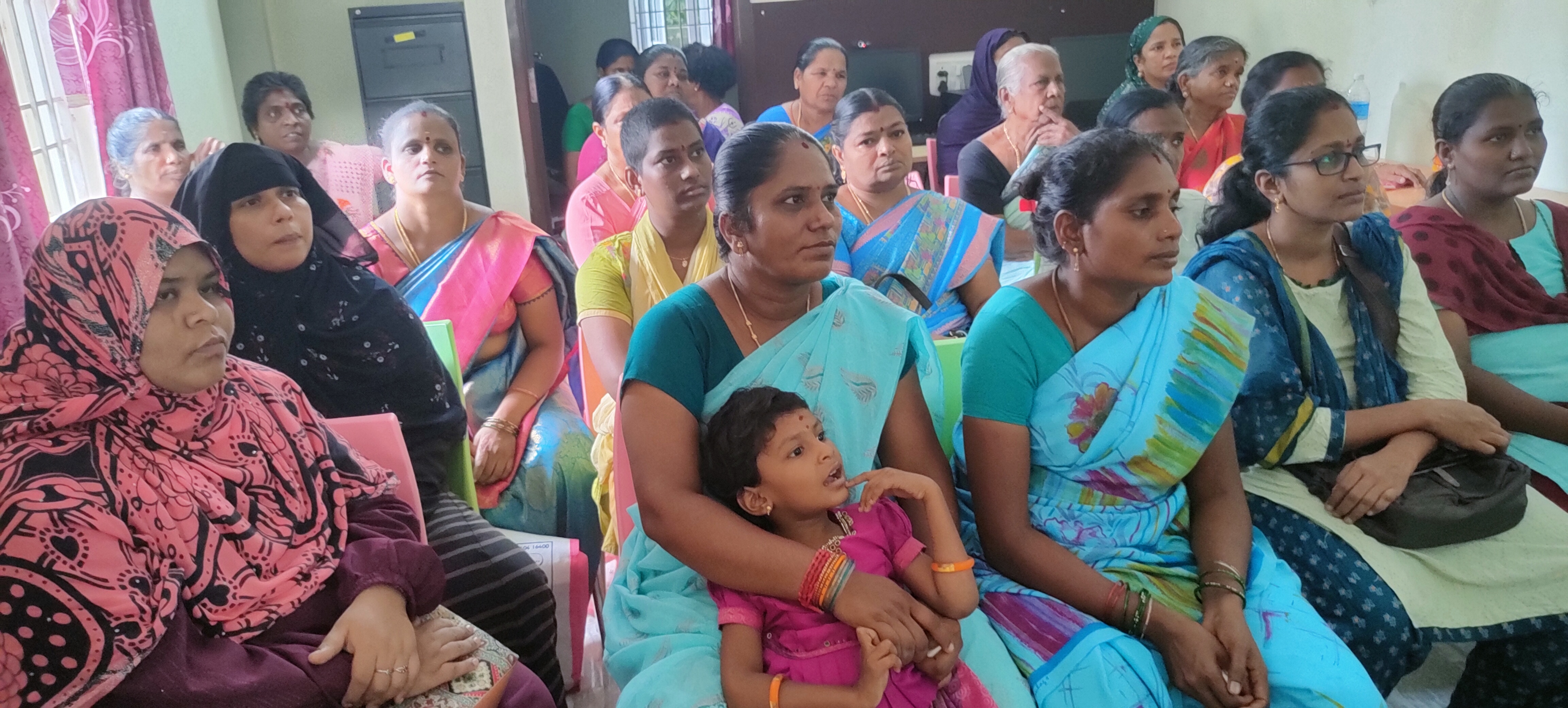 Women's empowerment meeting showing diverse participants in colorful traditional attire engaged in community discussion